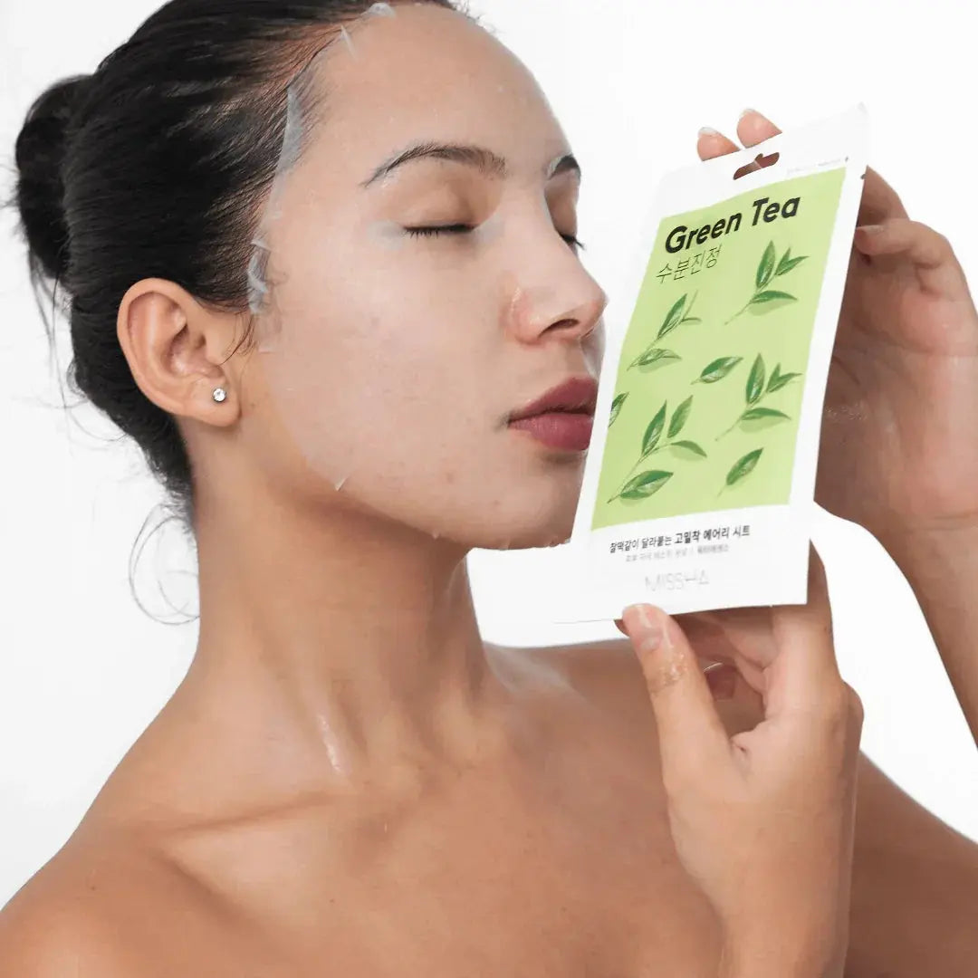 Kvinna med slutna ögon och sheet mask håller en grön förpackning Missha Green Tea sheet mask